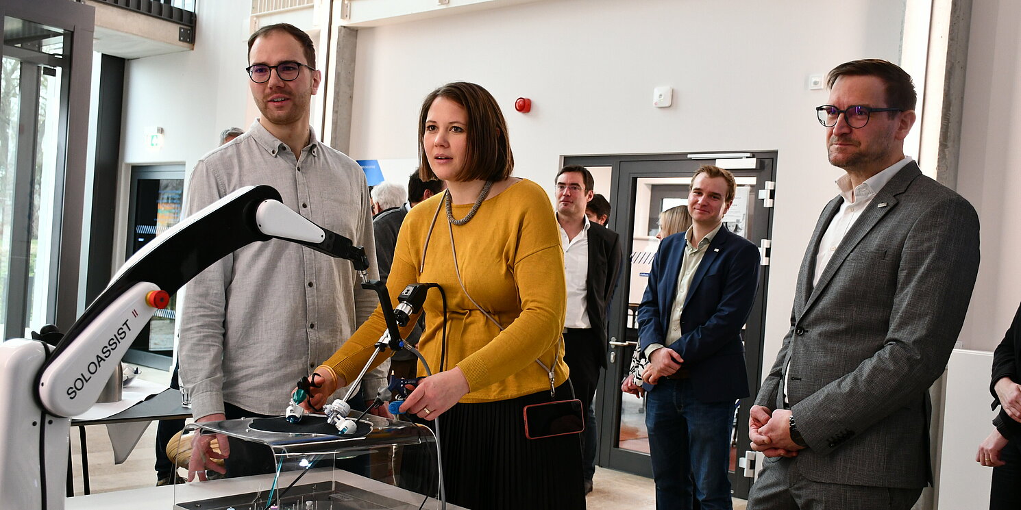 MdB Carolin Wagner durfte ihr medizinisches Können unter Beweis stellen. Foto: OTH Regensburg/Simone Grebler Eine Frau steht an einem Roboter, der eine Operation simuliert.